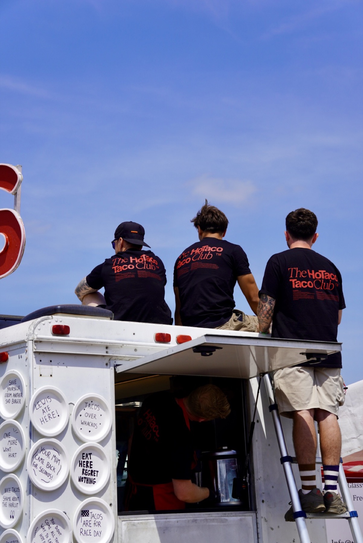 Three of the crew sat on the roof of the truck in Taco Club shirts.