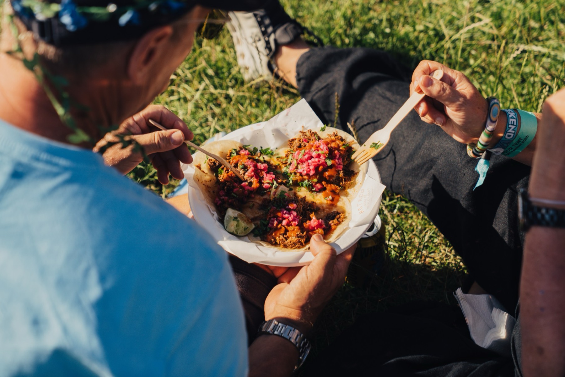 Two guests sat on the grass eating tacos in the late afternoon sun.